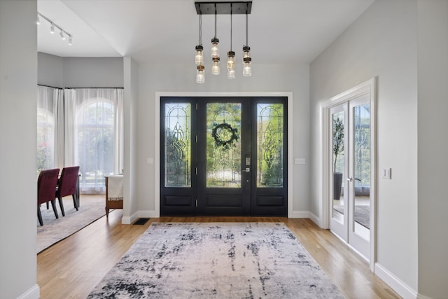 entryway with track lighting, light hardwood / wood-style flooring, and french doors