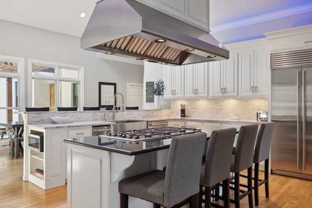 kitchen featuring white cabinets, light hardwood / wood-style flooring, a kitchen island, island range hood, and stainless steel appliances