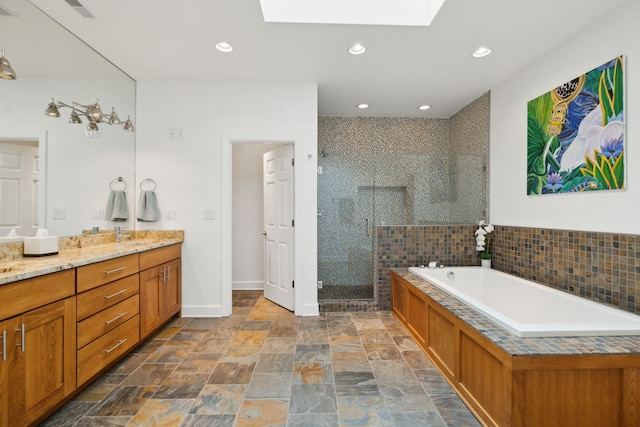 bathroom featuring a skylight, plus walk in shower, and vanity