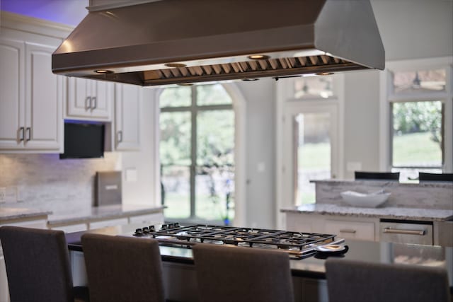 kitchen featuring white cabinets, plenty of natural light, island range hood, and backsplash