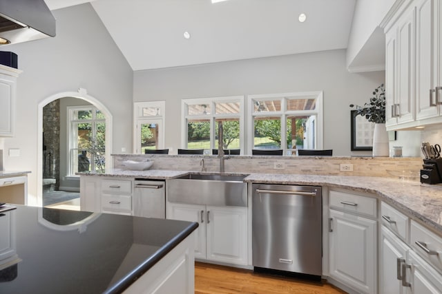 kitchen featuring stainless steel dishwasher, white cabinetry, a wealth of natural light, and vaulted ceiling