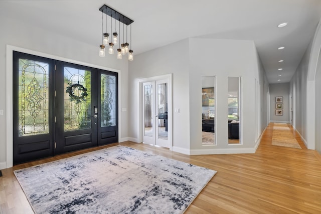 foyer entrance with french doors, wood-type flooring, and a notable chandelier