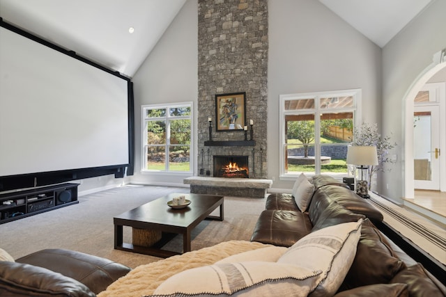 carpeted cinema with a healthy amount of sunlight, a fireplace, and high vaulted ceiling