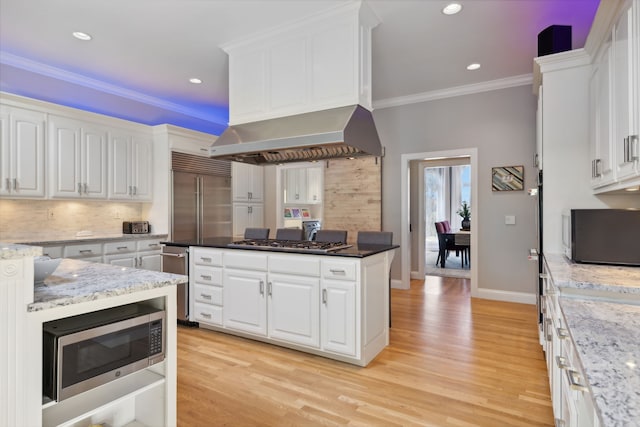 kitchen with white cabinets, stainless steel appliances, light hardwood / wood-style floors, and dark stone countertops