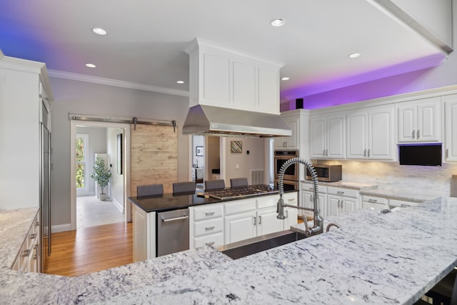 kitchen featuring white cabinets, sink, a barn door, light hardwood / wood-style floors, and stainless steel appliances