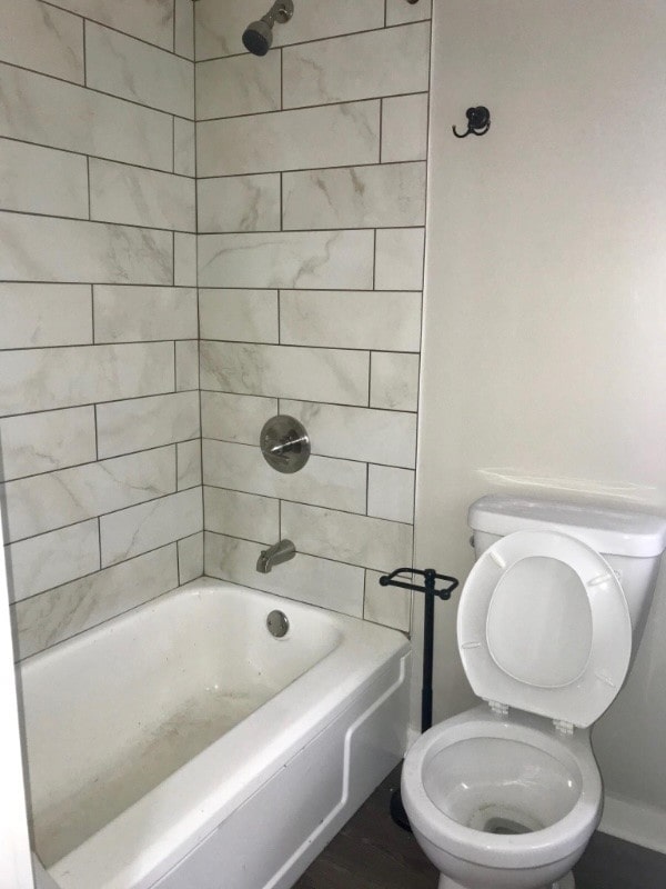 bathroom featuring toilet and tiled shower / bath