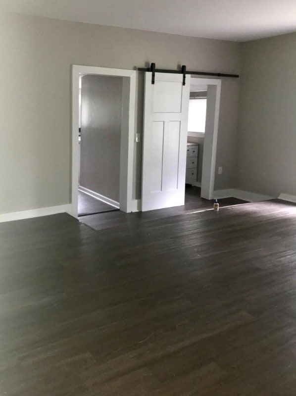 unfurnished room featuring a barn door and dark hardwood / wood-style floors