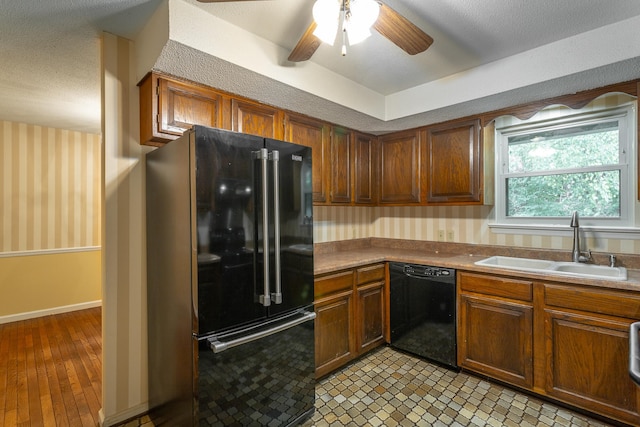 kitchen featuring a textured ceiling, black appliances, light hardwood / wood-style flooring, sink, and ceiling fan