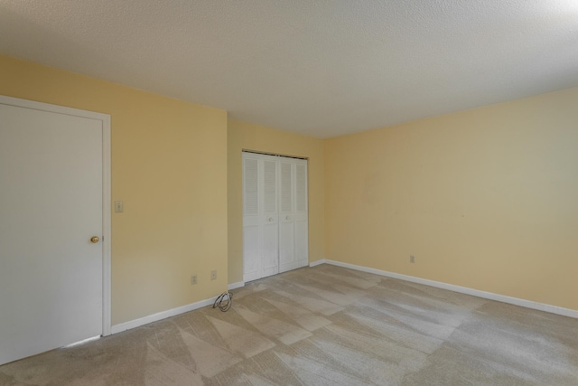 unfurnished bedroom featuring a textured ceiling, light colored carpet, and a closet