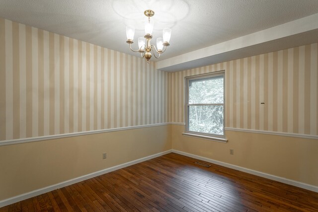 spare room featuring a textured ceiling, a notable chandelier, and hardwood / wood-style flooring