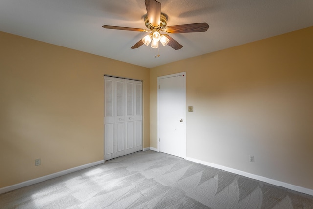 unfurnished bedroom featuring light colored carpet, ceiling fan, and a closet