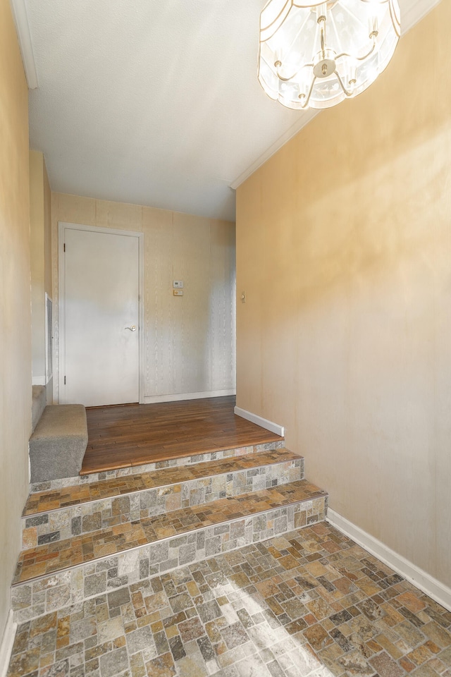 staircase with crown molding and a notable chandelier