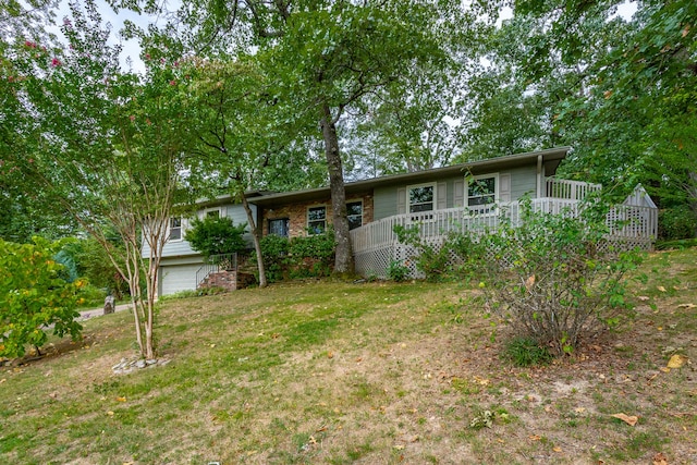 rear view of house featuring a lawn, a garage, and a deck