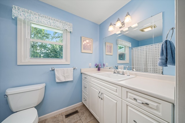 bathroom with toilet, vanity, a healthy amount of sunlight, and tile patterned floors