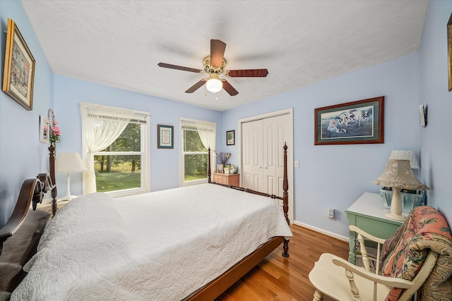 bedroom with ceiling fan, a textured ceiling, a closet, and wood-type flooring