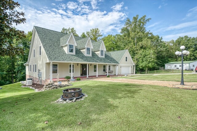 cape cod-style house featuring central AC, a porch, a garage, a front yard, and a fire pit