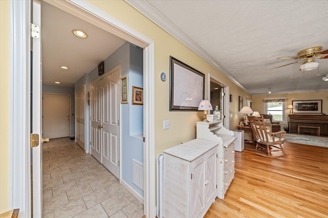 hall featuring a textured ceiling, crown molding, and light hardwood / wood-style flooring