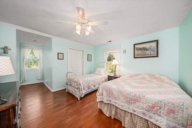 bedroom with ceiling fan, a textured ceiling, a closet, and dark hardwood / wood-style flooring