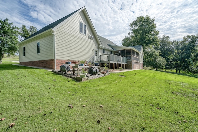 rear view of house featuring a sunroom, a lawn, and a wooden deck