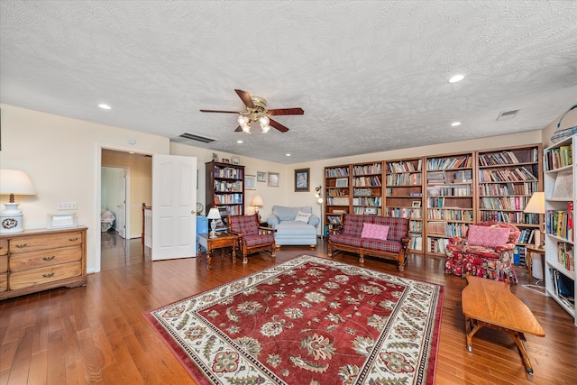 living area featuring hardwood / wood-style flooring, ceiling fan, and a textured ceiling