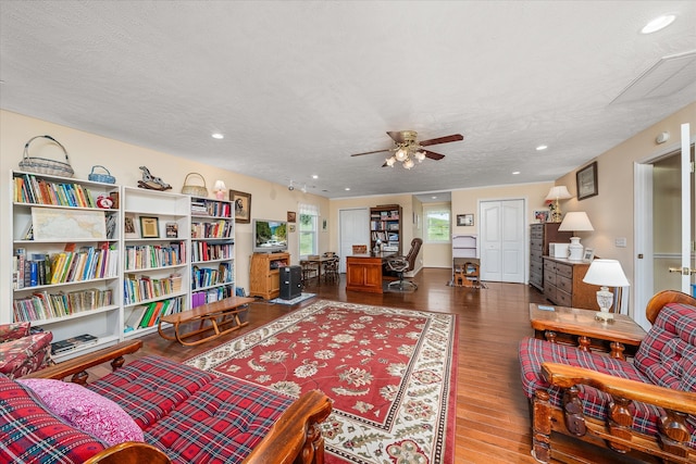 living room featuring ceiling fan, a textured ceiling, and dark hardwood / wood-style flooring