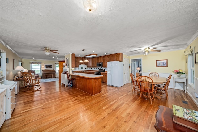 kitchen featuring stainless steel appliances, a textured ceiling, decorative light fixtures, and light hardwood / wood-style flooring