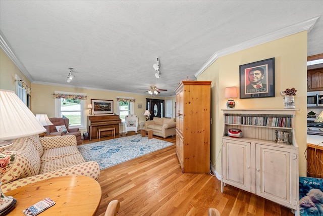 living room featuring light hardwood / wood-style flooring, rail lighting, ceiling fan, and crown molding