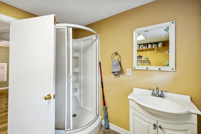 bathroom with a shower with shower door, hardwood / wood-style floors, and vanity