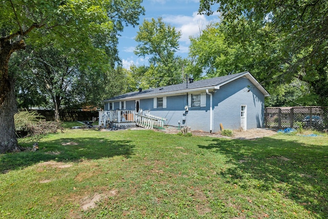 rear view of property featuring a deck and a lawn