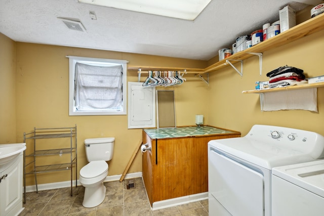 laundry room featuring a textured ceiling, independent washer and dryer, electric panel, and light tile patterned flooring