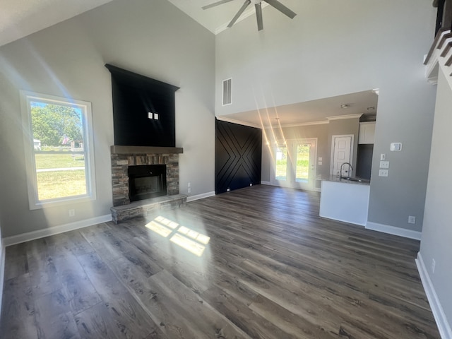 unfurnished living room with high vaulted ceiling, a healthy amount of sunlight, a fireplace, and dark hardwood / wood-style flooring