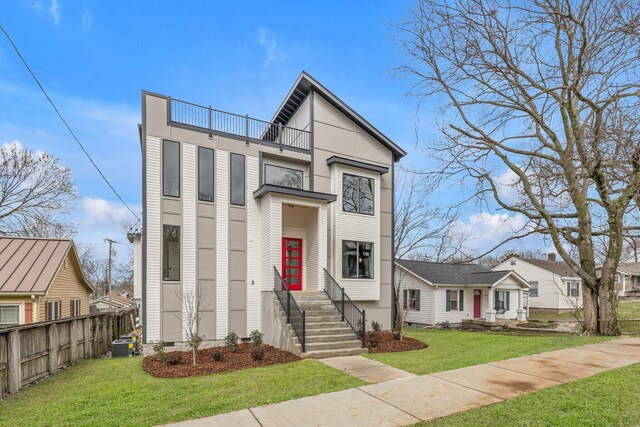 view of front of house featuring a balcony, a front yard, and central AC unit