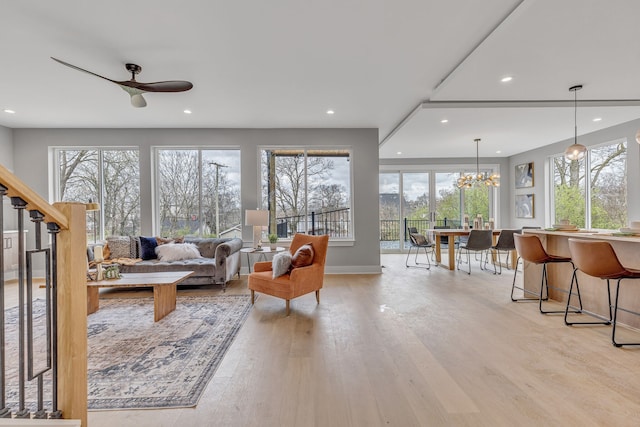 living room with light wood-type flooring, ceiling fan, and plenty of natural light