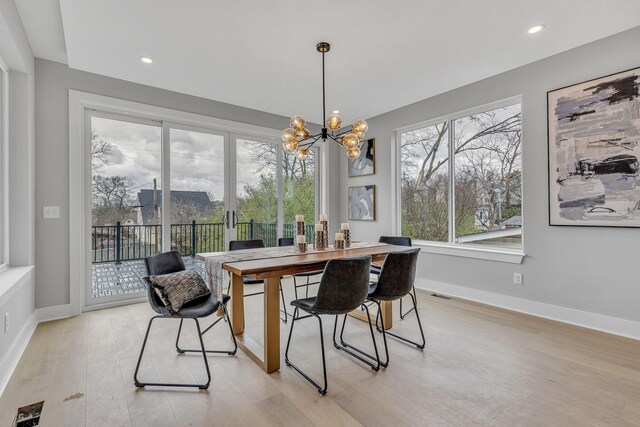 dining area with light hardwood / wood-style flooring and an inviting chandelier