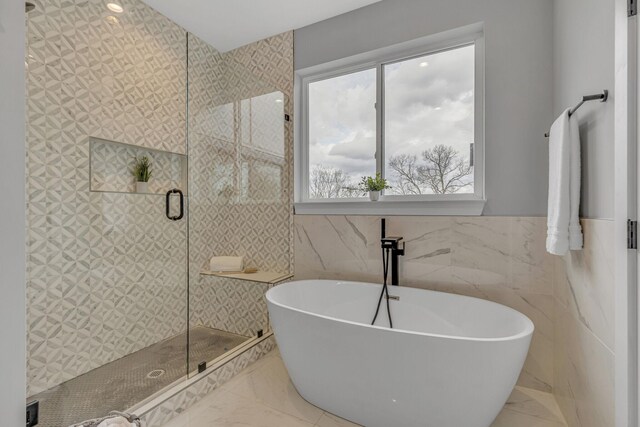 bathroom featuring tile walls and independent shower and bath