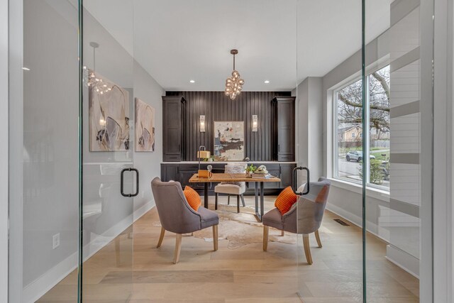 dining area featuring a healthy amount of sunlight, a notable chandelier, and light wood-type flooring