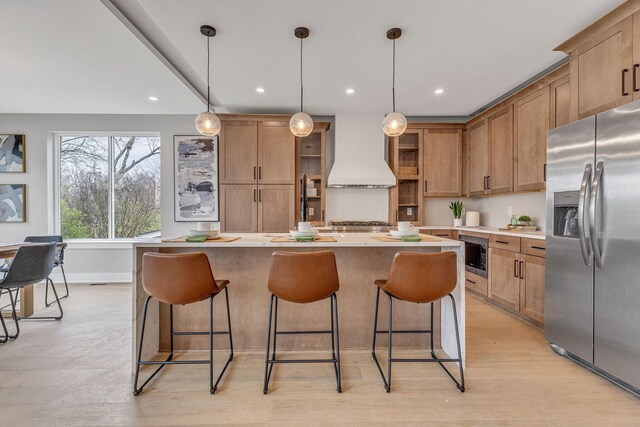 kitchen with a center island, custom range hood, a breakfast bar, and appliances with stainless steel finishes