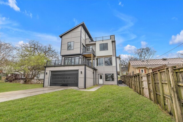 rear view of house featuring a balcony, a garage, and a yard