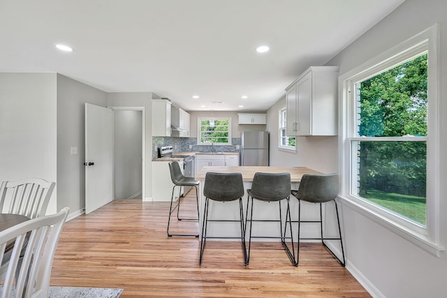 kitchen featuring white cabinetry, light hardwood / wood-style floors, appliances with stainless steel finishes, and a wealth of natural light