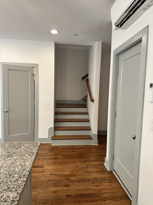 stairs with a wall mounted AC and hardwood / wood-style flooring