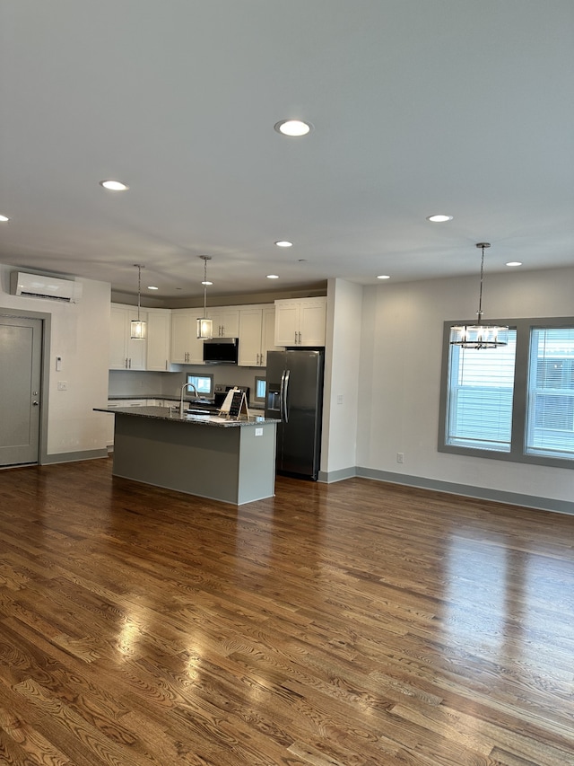 kitchen featuring dark hardwood / wood-style floors, a center island with sink, stainless steel appliances, and hanging light fixtures