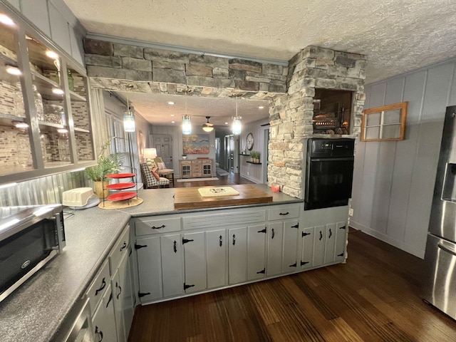 kitchen featuring dark hardwood / wood-style floors, a textured ceiling, stainless steel appliances, and hanging light fixtures