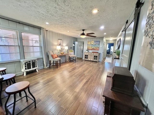 living room featuring ceiling fan, hardwood / wood-style flooring, and a textured ceiling