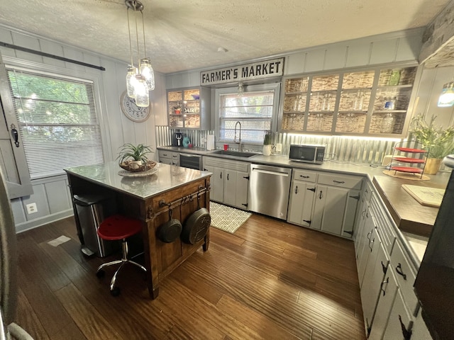 kitchen with a center island, appliances with stainless steel finishes, dark hardwood / wood-style flooring, sink, and a textured ceiling