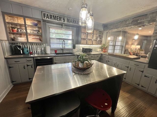 kitchen with white cabinets, a center island, sink, dark wood-type flooring, and pendant lighting