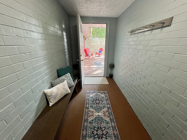 doorway to outside featuring brick wall and a textured ceiling