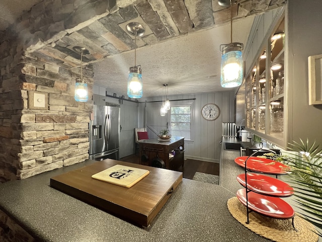 kitchen with stainless steel refrigerator with ice dispenser, a textured ceiling, and a barn door