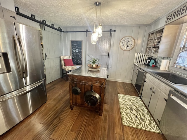 kitchen with a barn door, stainless steel appliances, and dark hardwood / wood-style floors