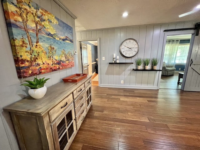 hall featuring a textured ceiling, hardwood / wood-style flooring, and a barn door