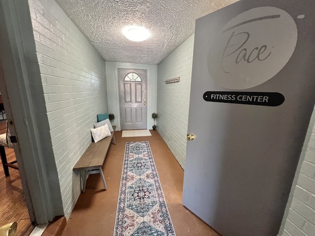 entryway featuring brick wall and a textured ceiling